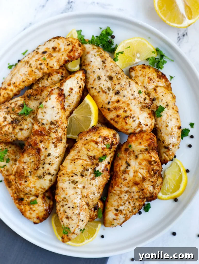 Crispy Air Fryer Lemon Pepper Chicken 2 Top down view of lemon pepper chicken on a plate, garnished with fresh parsley and lemon wedges.