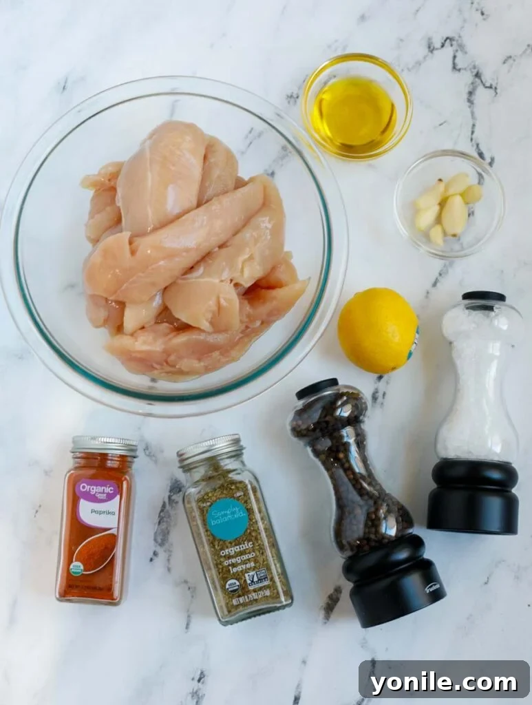 Crispy Air Fryer Lemon Pepper Chicken 3 Top down view of ingredients for air fryer lemon pepper chicken recipe, including chicken tenders, lemon, olive oil, and various spices.