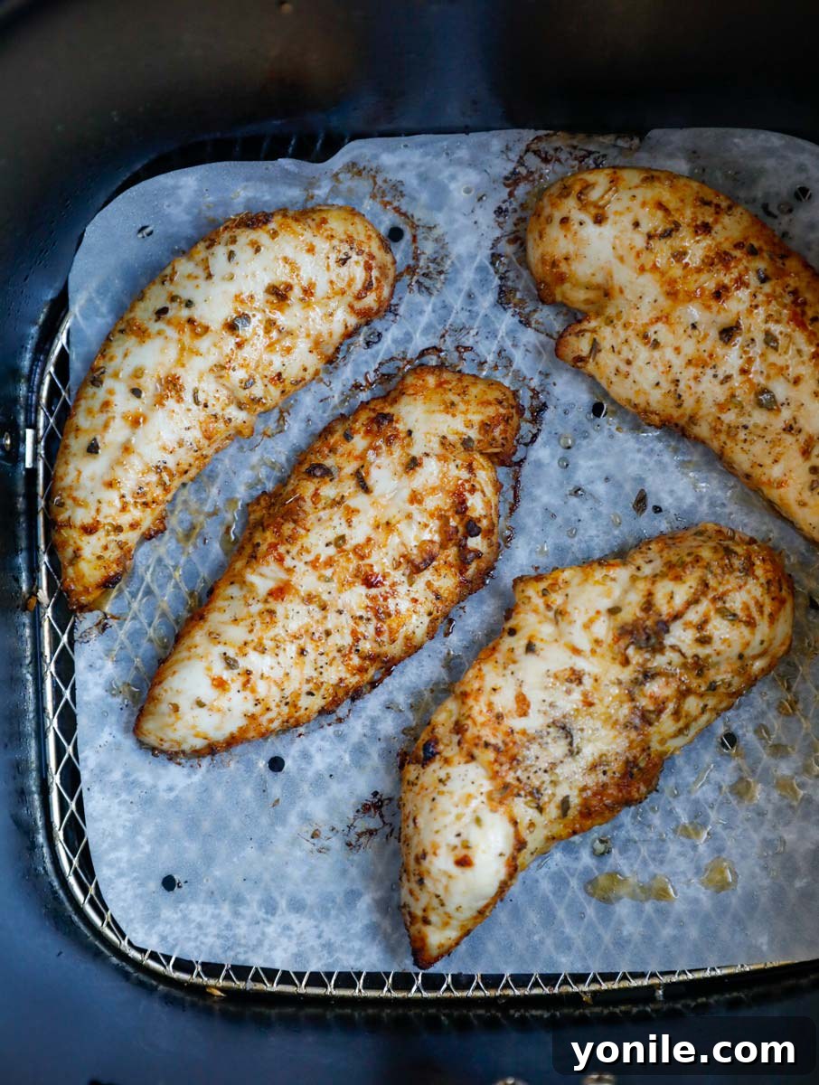 Crispy Air Fryer Lemon Pepper Chicken 6 Cooked lemon pepper chicken tenders in an air fryer basket, showing a golden brown, crispy exterior.