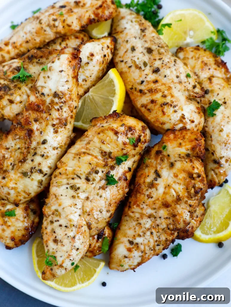 Crispy Air Fryer Lemon Pepper Chicken 7 Top down shot of lemon pepper chicken on a plate with fresh lemon wedges and parsley.