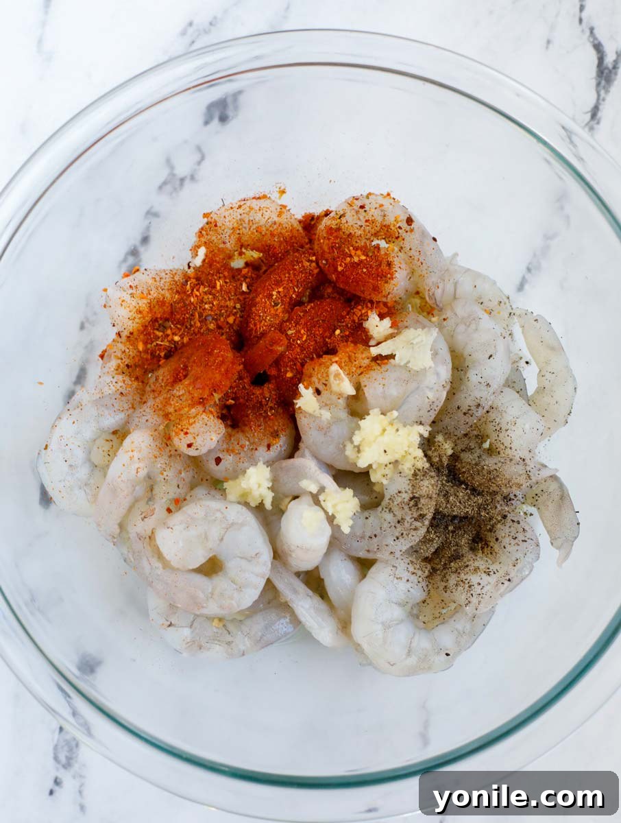 Raw shrimp being mixed with seasoning in a bowl.
