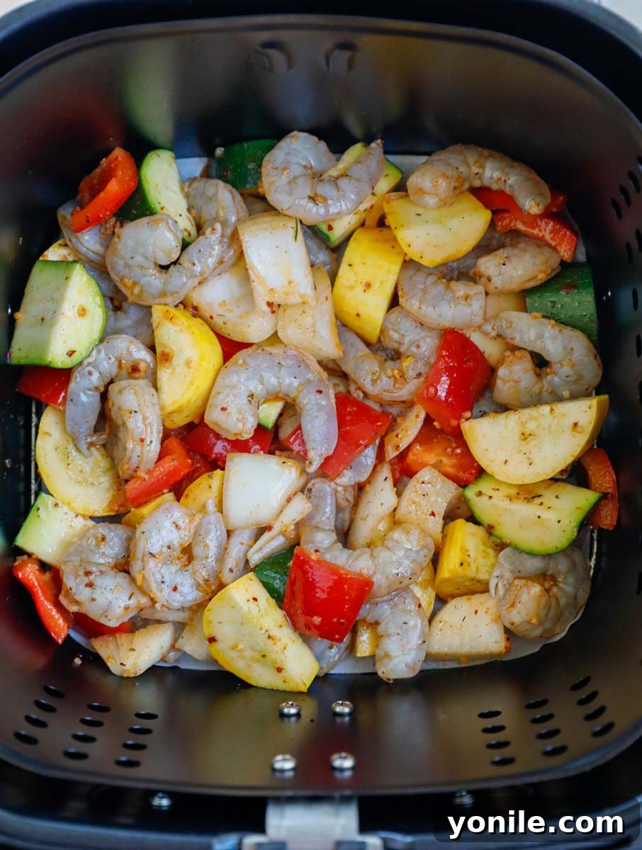 Raw marinated shrimp and vegetables placed in an air fryer basket.
