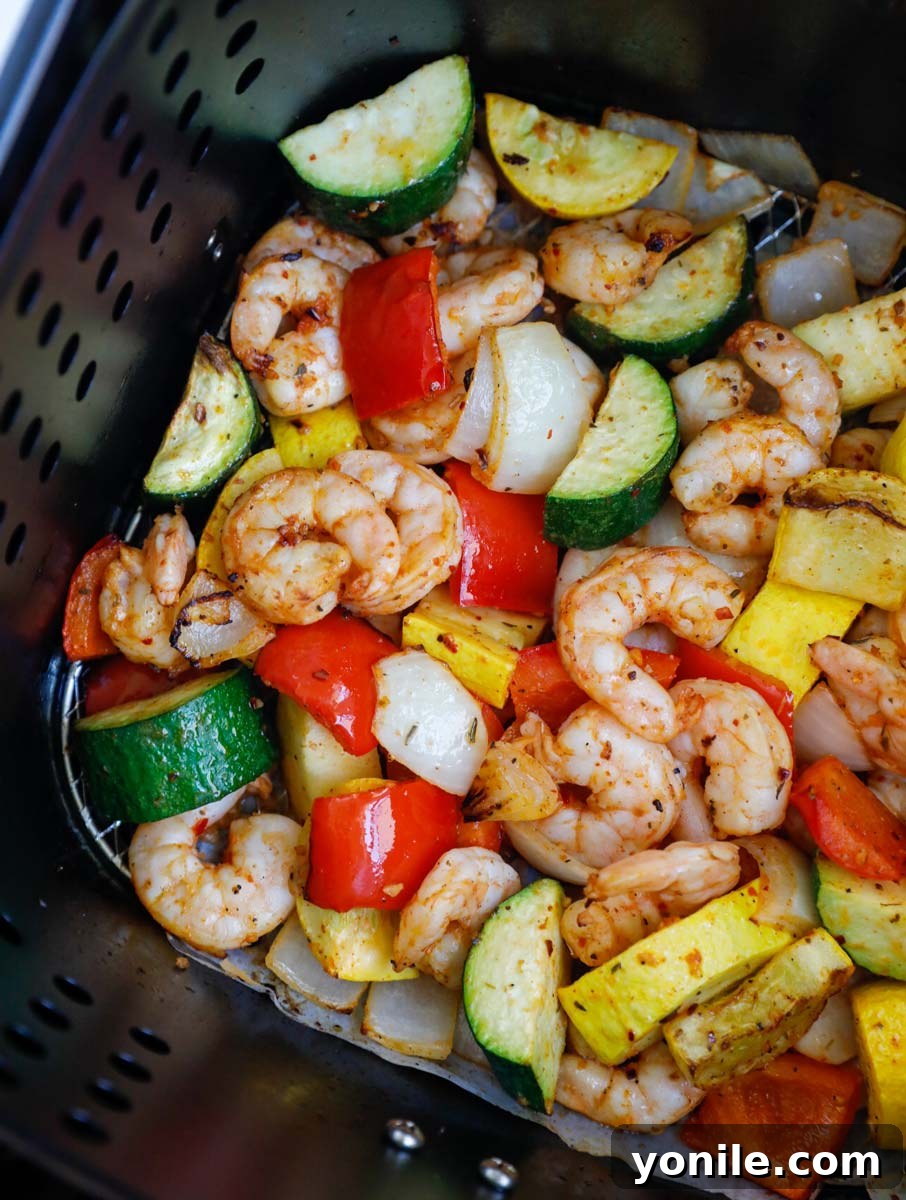 Cooked air fryer shrimp and vegetables, golden and tender, in the air fryer basket.