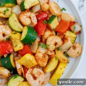 Top down shot of air fryer shrimp and vegetables on a plate.
