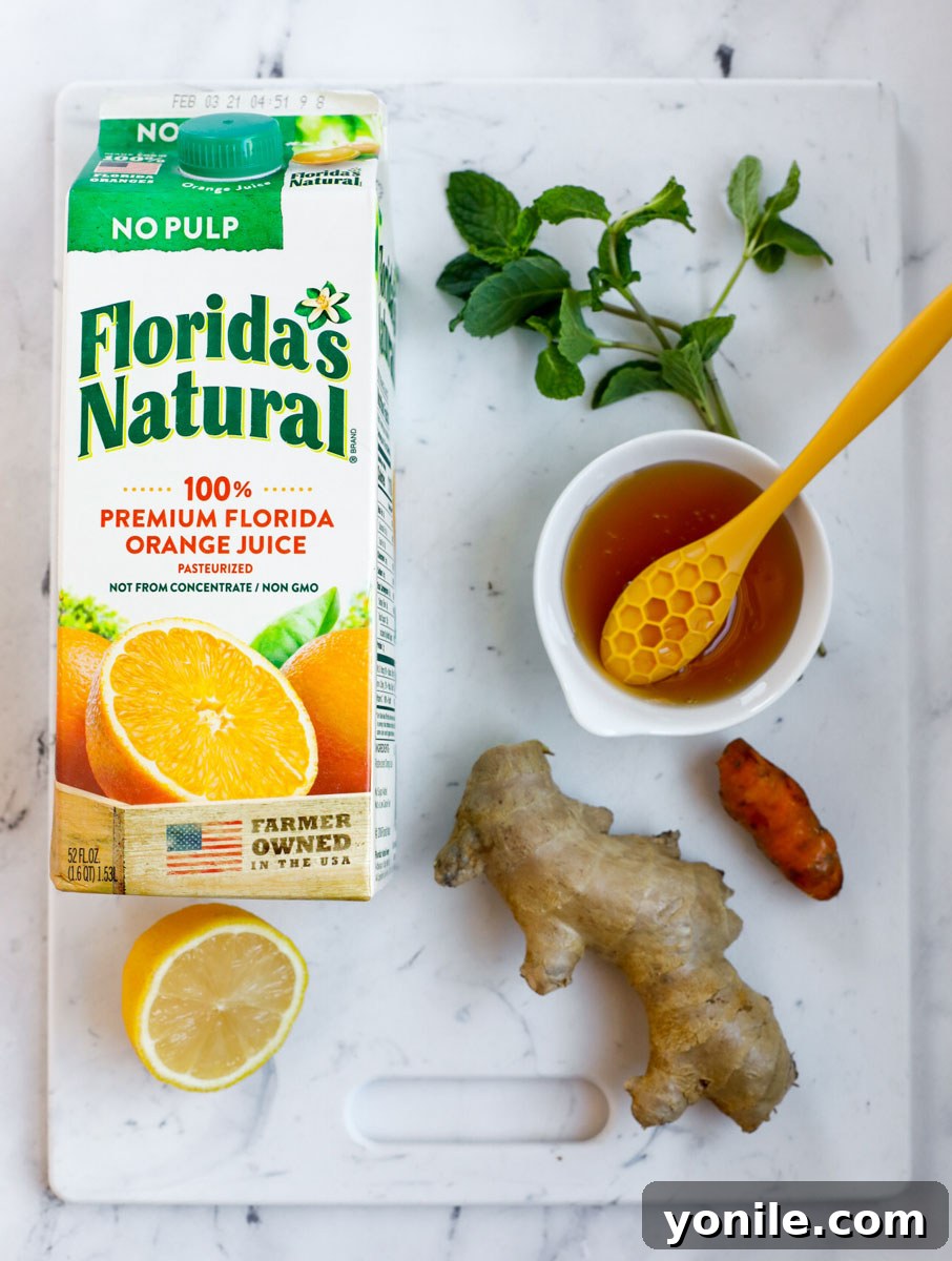 Citrus Immune Shield 4 An organized top-down arrangement of all the fresh ingredients needed for the Orange-Ade Immune Booster Drink: Florida's Natural orange juice, fresh ginger, fresh turmeric, raw honey, and a bright yellow lemon.