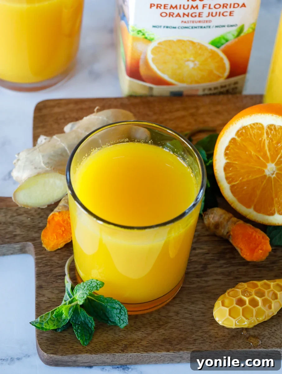 Citrus Immune Shield 7 A beautifully composed shot of the Orange-Ade Immune Booster Drink in a glass, surrounded by all the fresh ingredients used to make it: vibrant oranges, golden turmeric roots, and fresh ginger.