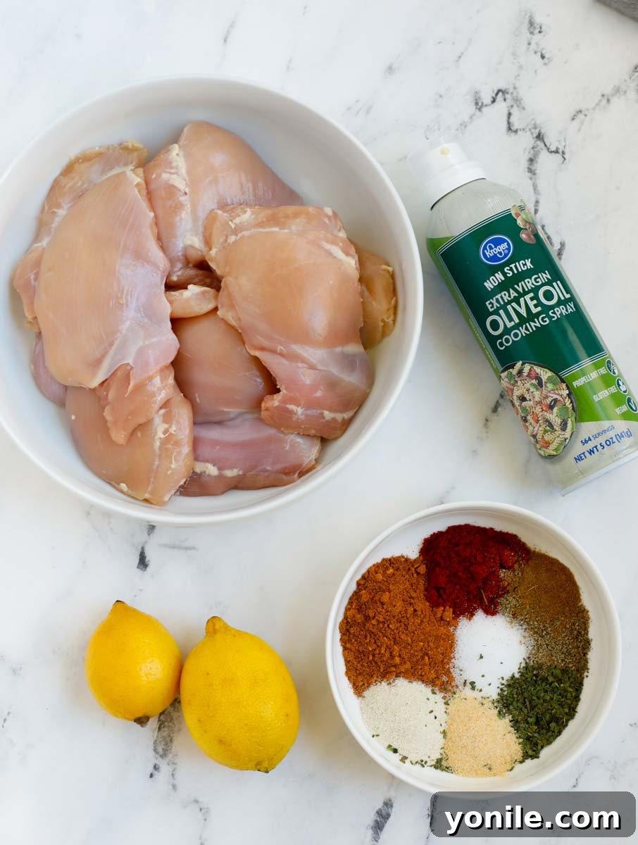 Crispy Air Fryer Chicken Thighs 3 A flat lay of all ingredients for air fryer boneless chicken thighs, including chicken, spices, and lemons.