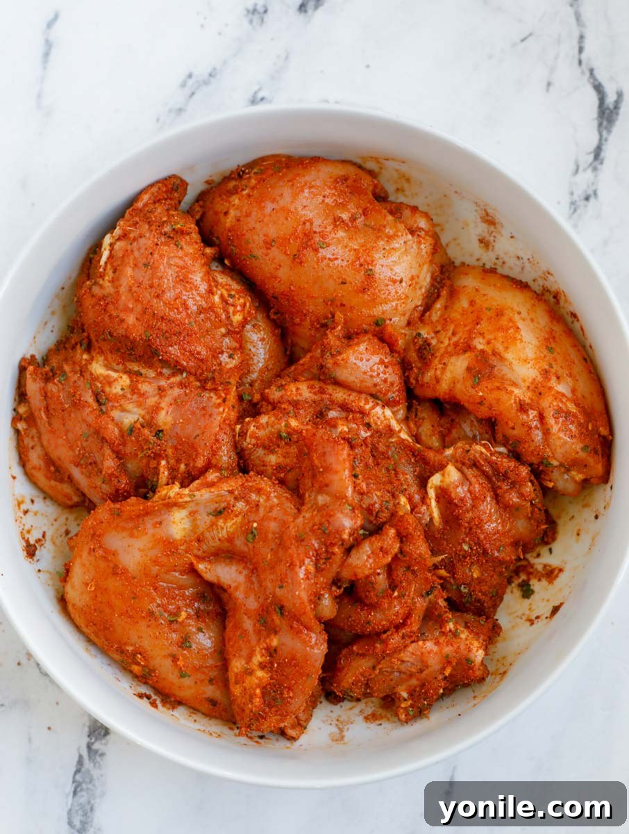 Crispy Air Fryer Chicken Thighs 5 Chicken thighs marinating in a bowl with spices and lemon.