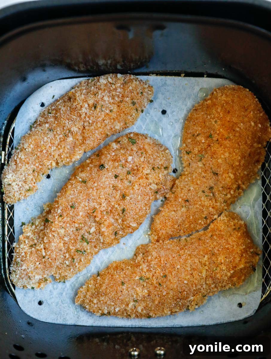 Top down view of crispy chicken tenders cooking in an air fryer.