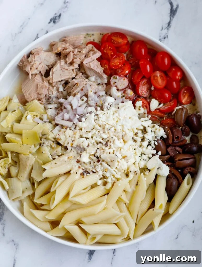 Mediterranean Tuna Pasta Salad 4 Overhead shot of cooked pasta and chopped veggies in a large mixing bowl, ready for the dressing.