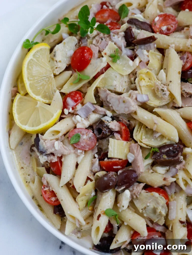 Mediterranean Tuna Pasta Salad 6 Overhead view of a generous serving of Greek tuna pasta salad in a large white bowl, garnished with fresh herbs.