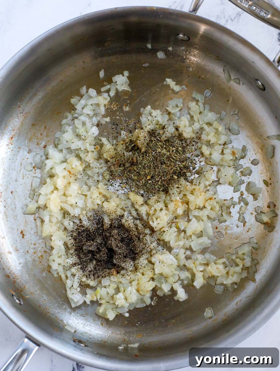 Cooking diced onions and minced garlic in a pan to start the sauce base.