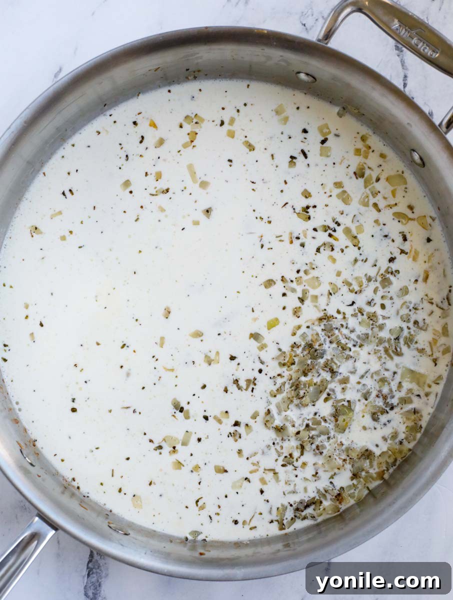 Adding heavy cream to the pan with sautéed aromatics for the creamy sauce.