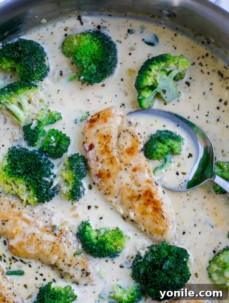 A spoon dipping into a pot of freshly made creamy chicken broccoli, showcasing its rich texture.