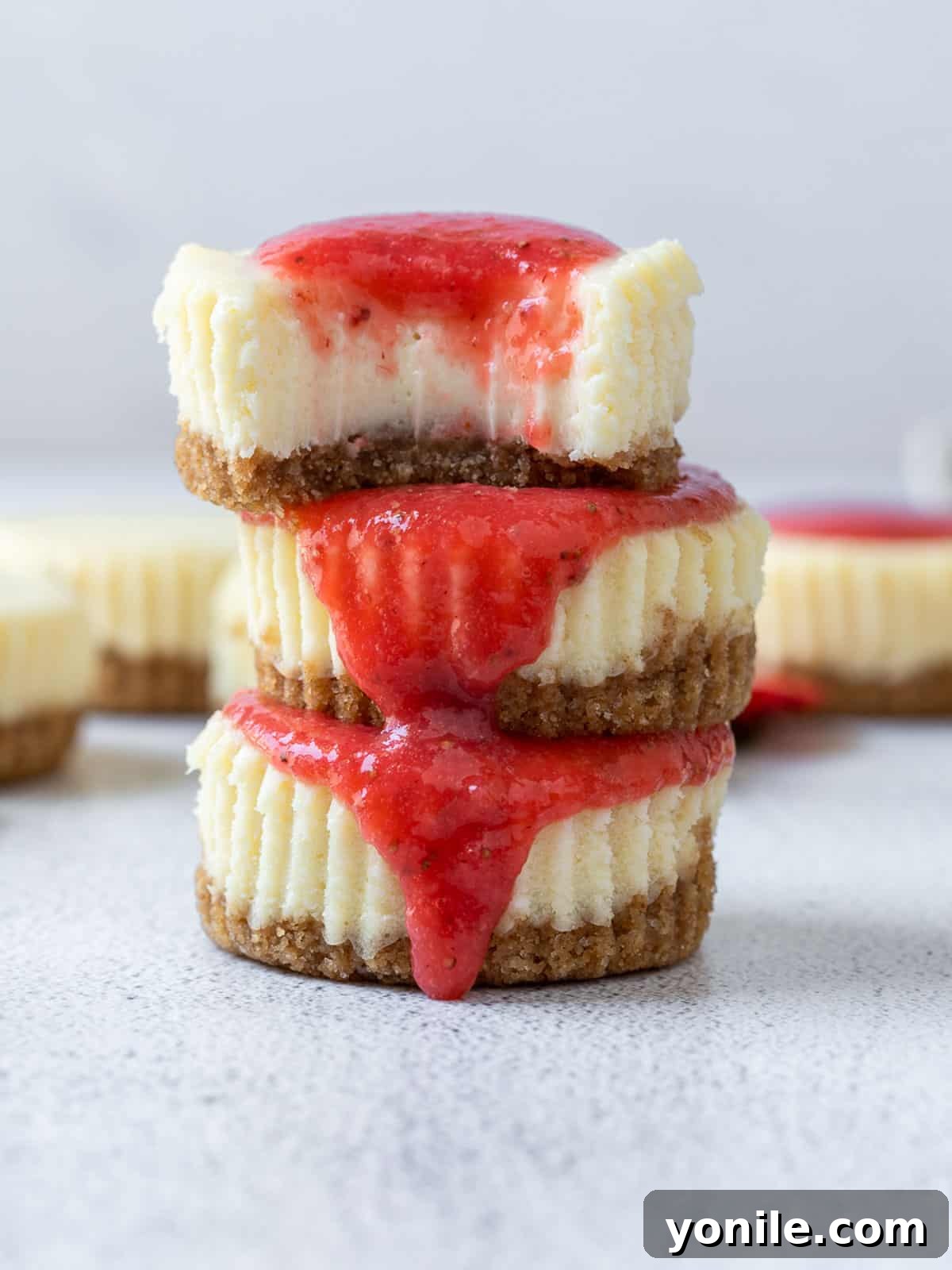 Three perfectly stacked mini strawberry cheesecakes with fresh strawberry topping, showcasing their individual charm.