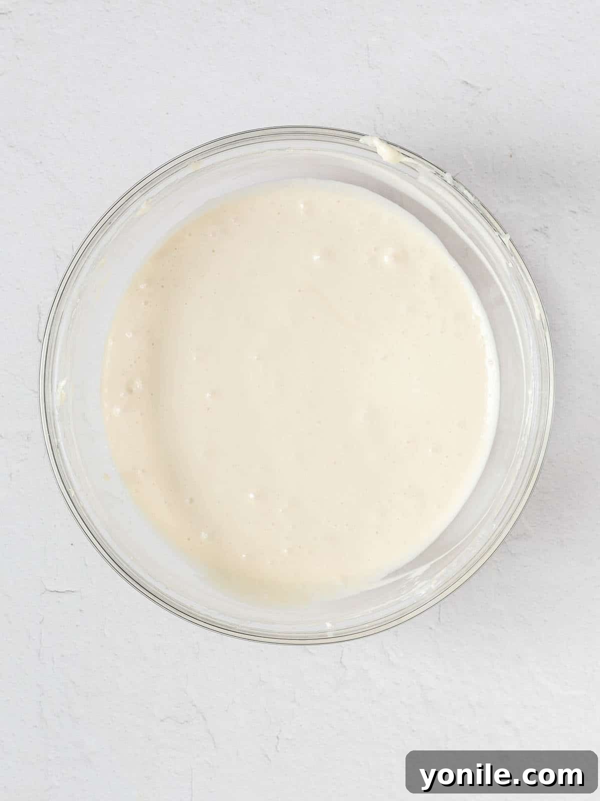 A large bowl filled with smooth, creamy cheesecake filling, ready for baking.