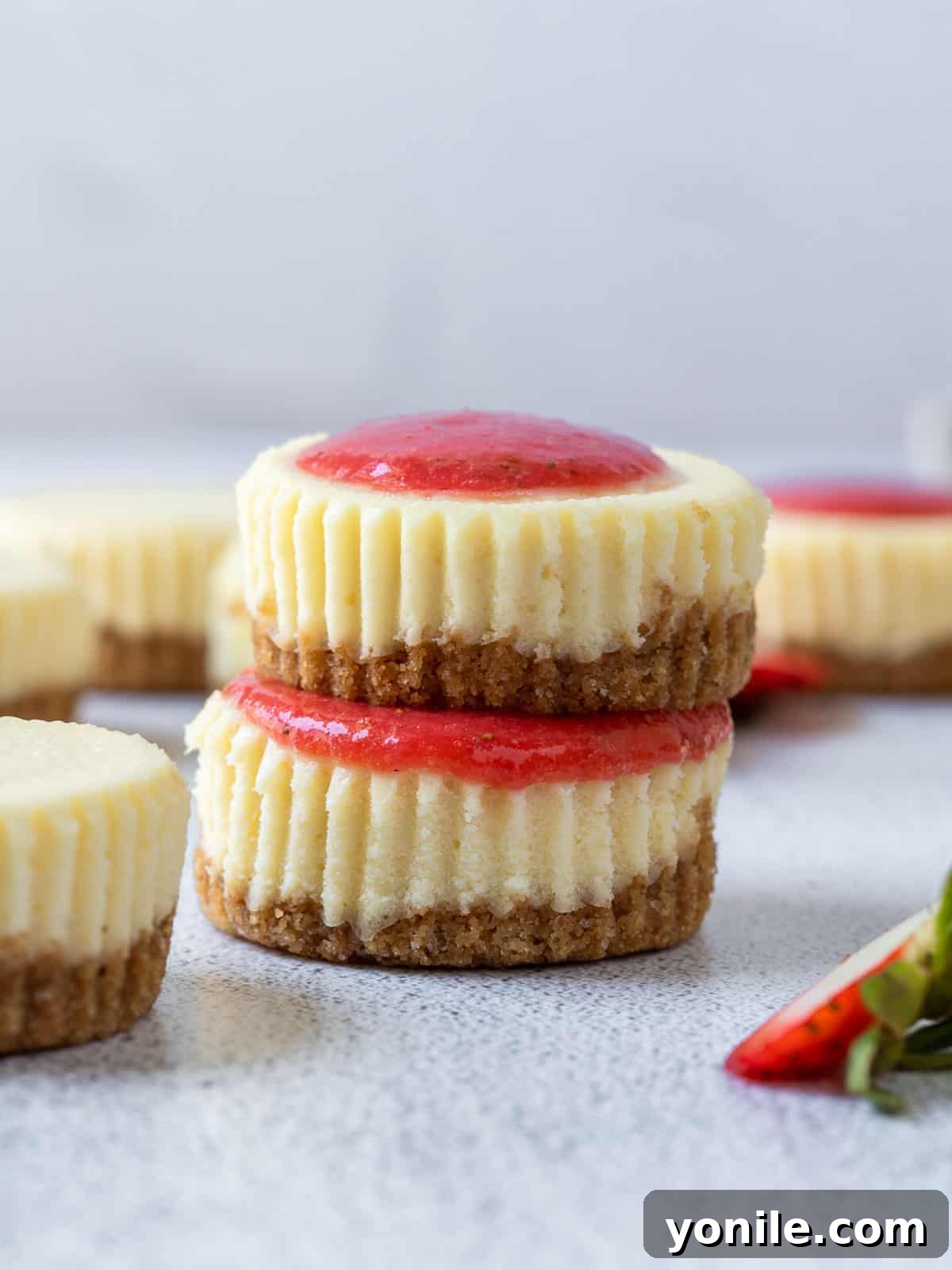 Two perfectly portioned mini cheesecakes, one with a luscious strawberry topping, stacked elegantly.