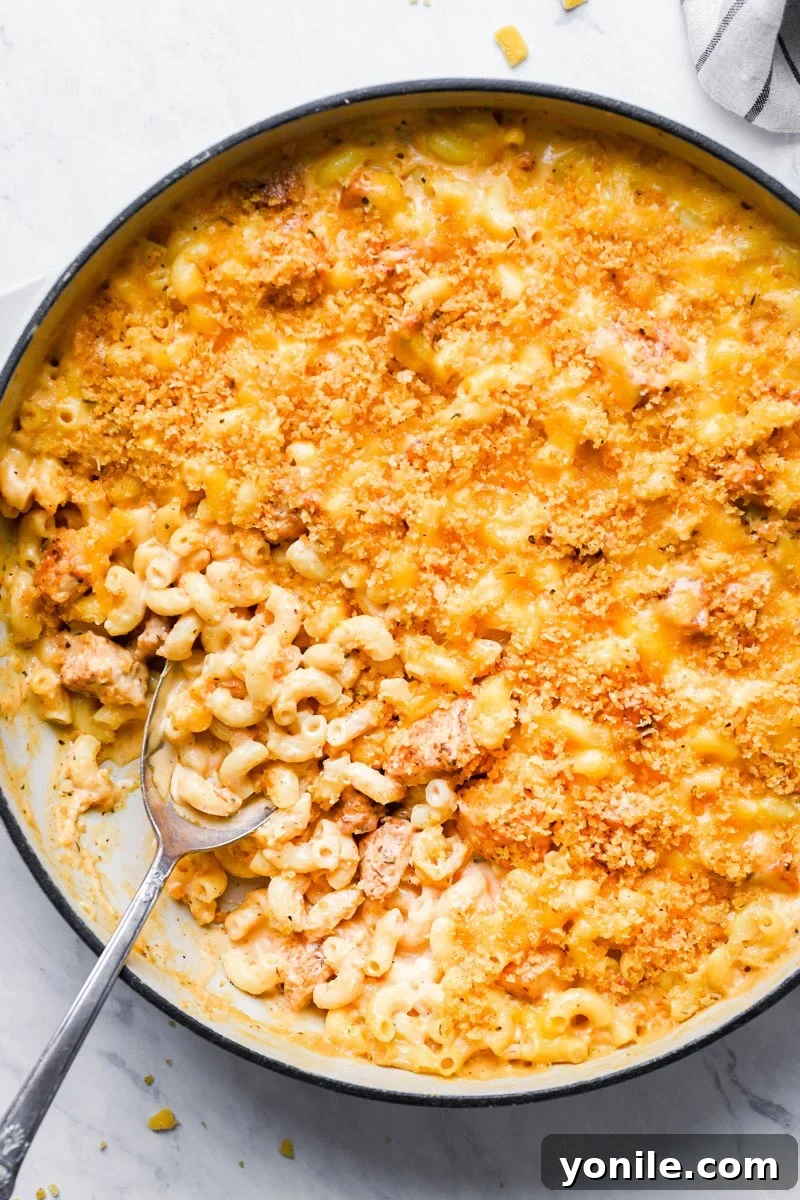Top-down shot of a large skillet filled with baked Cajun Chicken Mac and Cheese, garnished with fresh herbs.