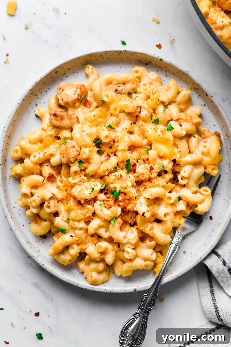 Serving of Cajun Chicken Mac and Cheese on a white plate, garnished with fresh parsley.