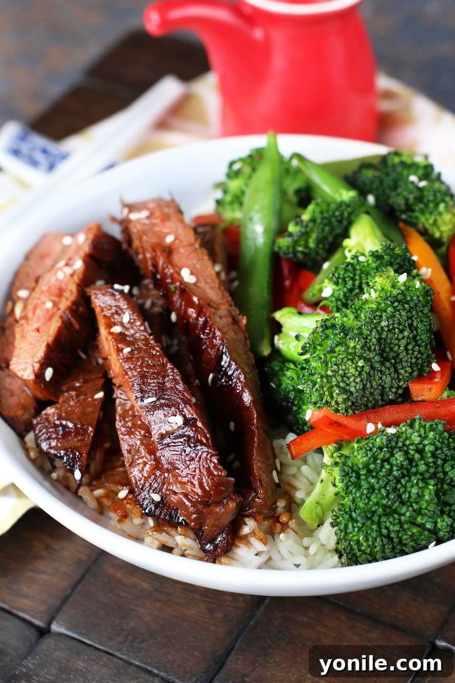 Sizzling Soy Flank Steak Stir-Fry 4 Image of Soy Marinated Steak Stir-Fry in a white bowl with broccoli and a red soy sauce container.