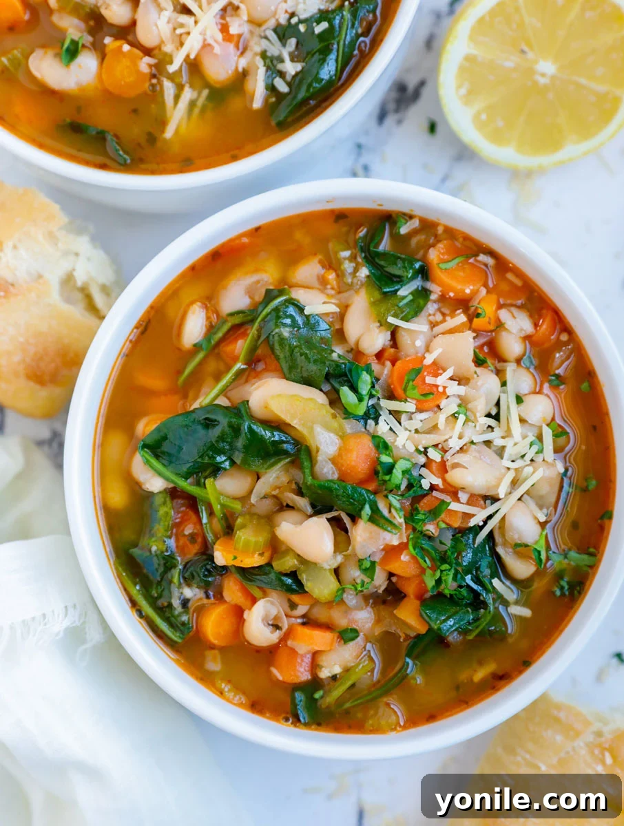 An inviting overhead shot of a rustic bowl filled with steaming Tuscan White Bean Soup, garnished with fresh parsley, placed on a wooden table alongside slices of crusty bread, inviting a comforting meal.