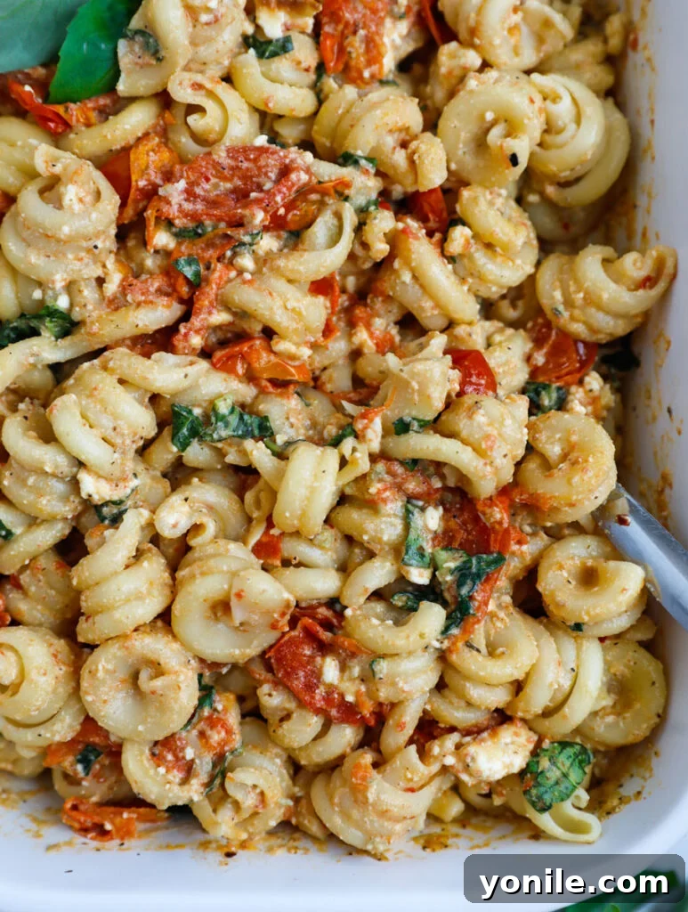 Close-up view of the creamy Baked Feta Pasta in a baking dish, showcasing its rich texture and fresh basil garnish.