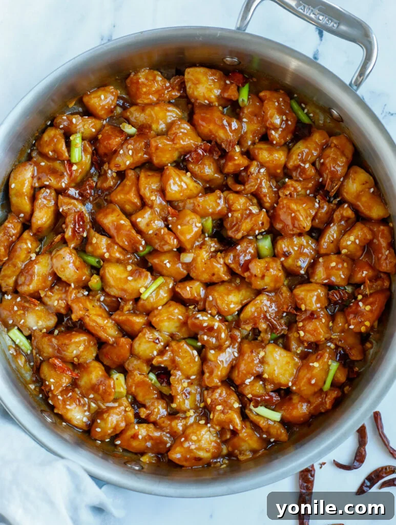 No Fuss General Tsos Chicken 2 Overhead photo of saucy general tso chicken in a skillet, garnished with green onions and sesame seeds.
