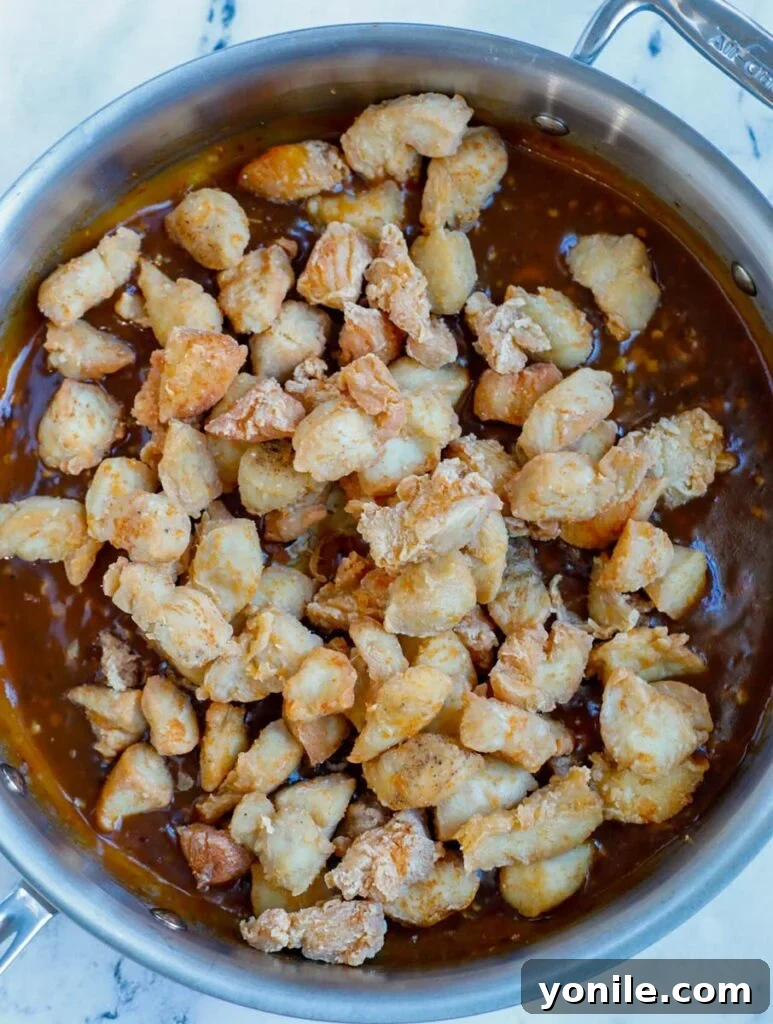 No Fuss General Tsos Chicken 11 Chicken being added into the rich General Tso's sauce in a skillet for coating.