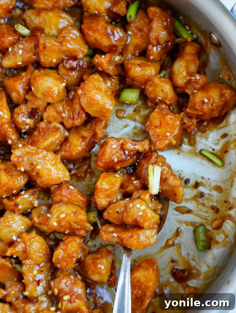 No Fuss General Tsos Chicken 14 Close up of a spoonful of crispy general tso chicken, showcasing its glossy sauce and tender texture.