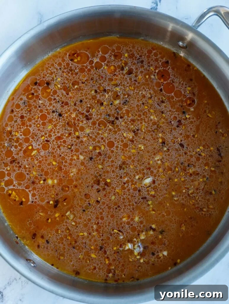 No Fuss General Tsos Chicken 9 Sauce coming to a boil and thickening in a skillet, creating a rich glaze.
