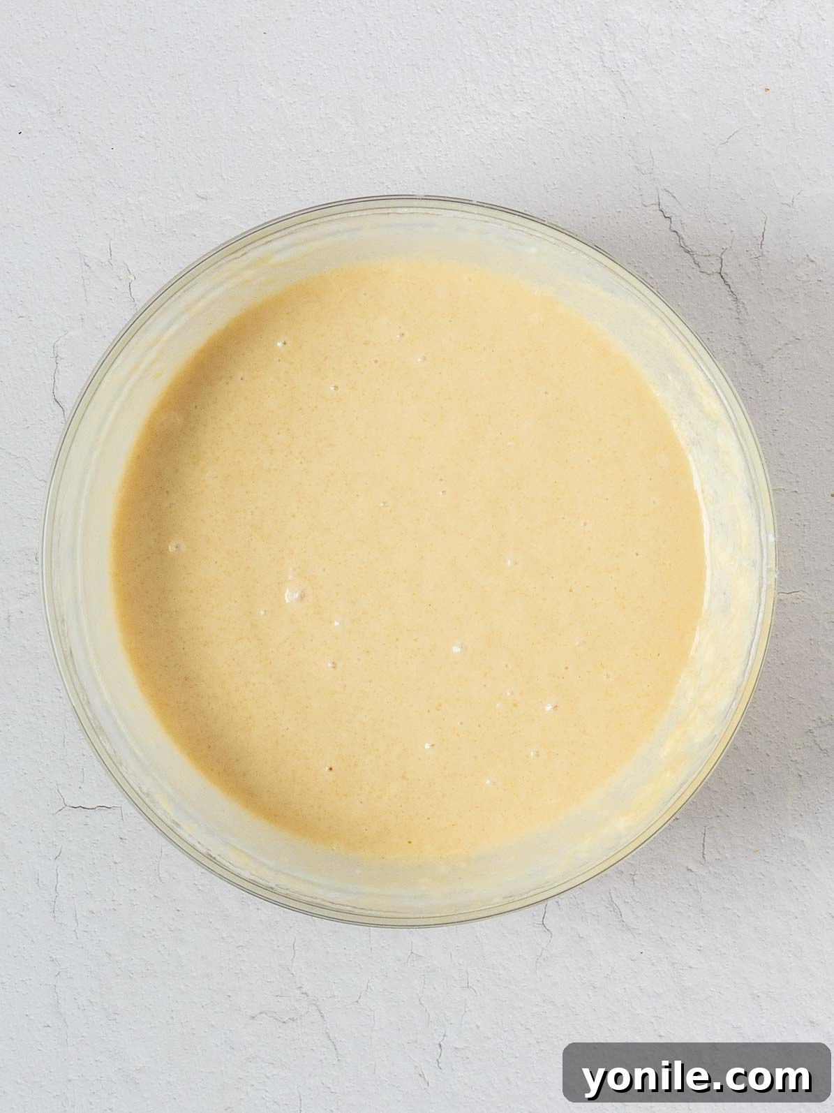 A smooth, golden cake batter sits in a mixing bowl, ready for the next step of baking.