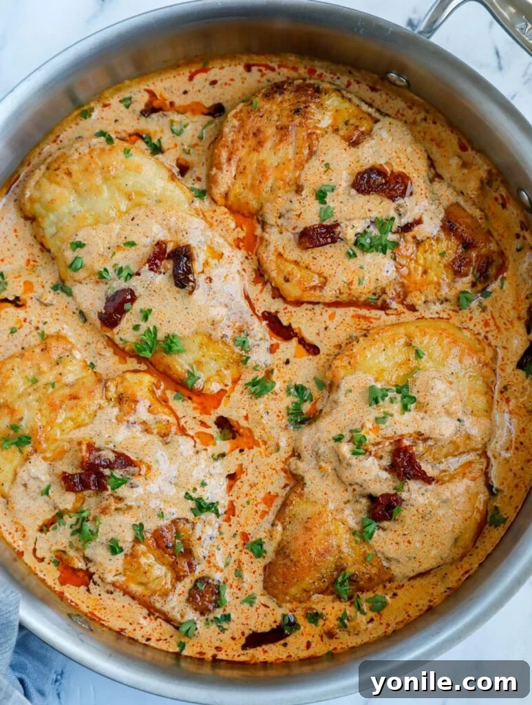 A large skillet filled with creamy Cajun chicken, topped with fresh parsley, ready to be served from the pan.
