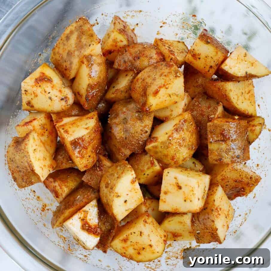 Crispy Air Fryer Potato Cubes 5 Diced potatoes in a bowl, evenly coated with olive oil and a savory seasoning blend, ready for air frying.