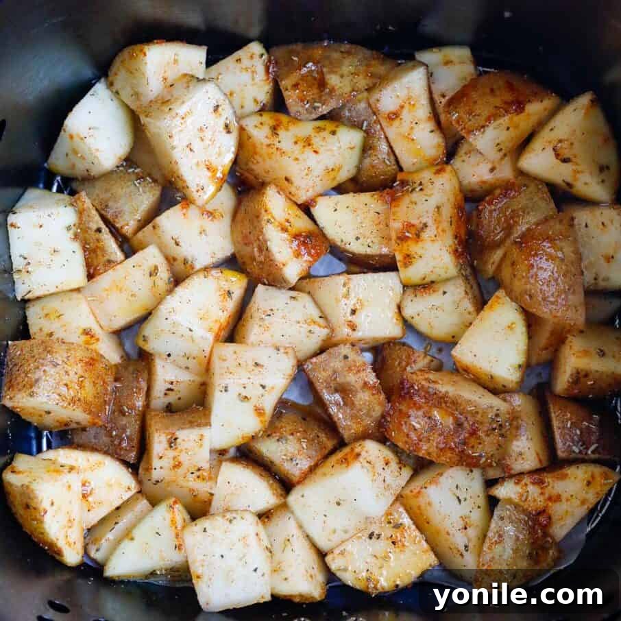 Crispy Air Fryer Potato Cubes 6 Seasoned potatoes spread in a single layer within an air fryer basket, ready for cooking.