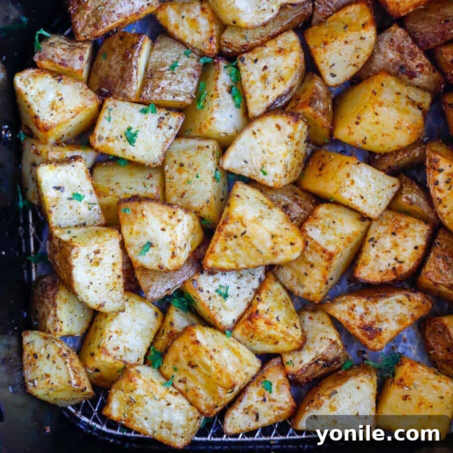 Crispy Air Fryer Potato Cubes 7 Golden-brown and crispy air fryer potatoes glistening inside an air fryer basket after cooking, ready to be served.