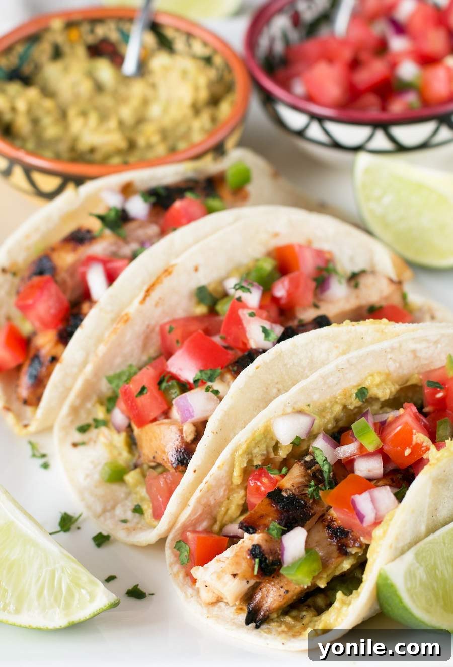 Three perfectly arranged Mexican Chicken Tacos on a white plate, showcasing the grilled chicken and fresh toppings.