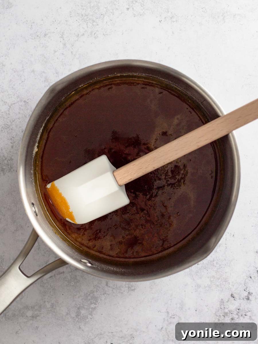 Close-up of fully caramelized sugar, a deep copper color, swirling smoothly inside a saucepan, indicating it's ready for the next step.