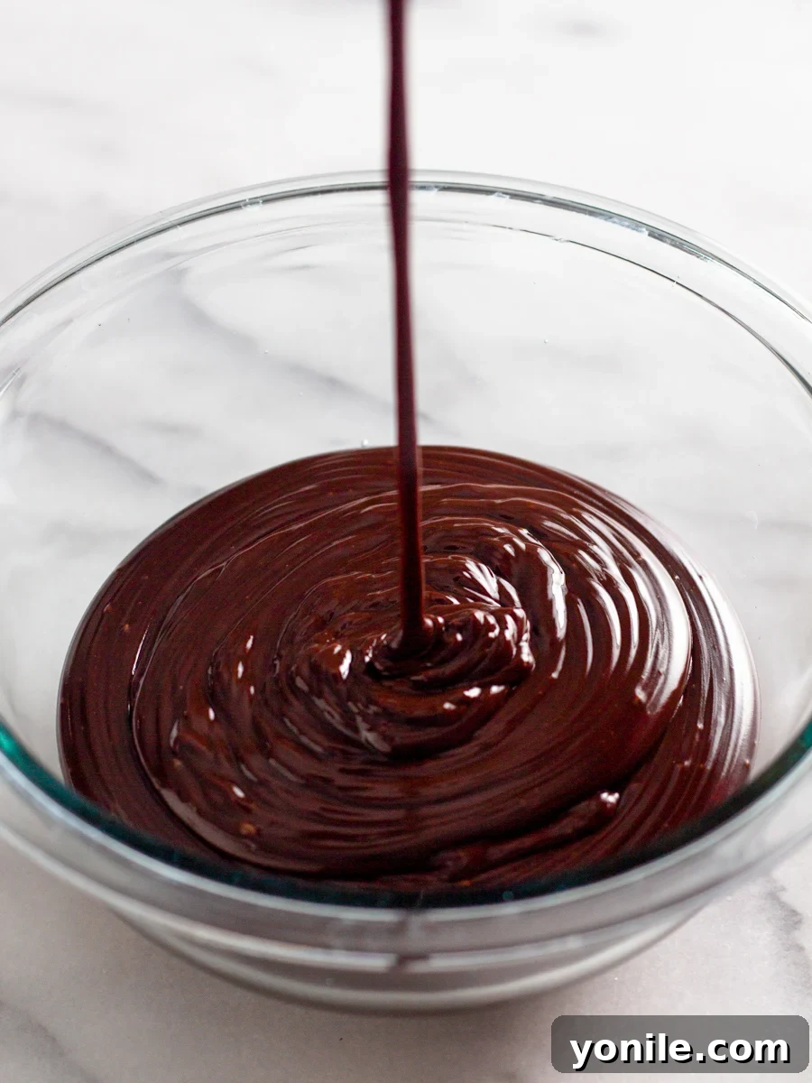 Mastering Chocolate Ganache 7 Glossy chocolate ganache being drizzled artfully into a bowl, showcasing its smooth consistency.