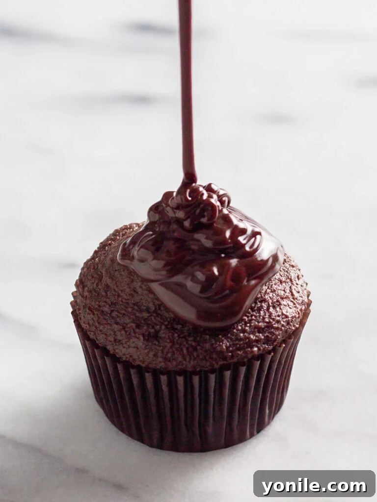 Mastering Chocolate Ganache 8 A cupcake adorned with a generous, glossy pour of chocolate ganache.