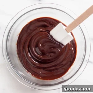 Mixing chocolate ganache in a bowl with a spatula.