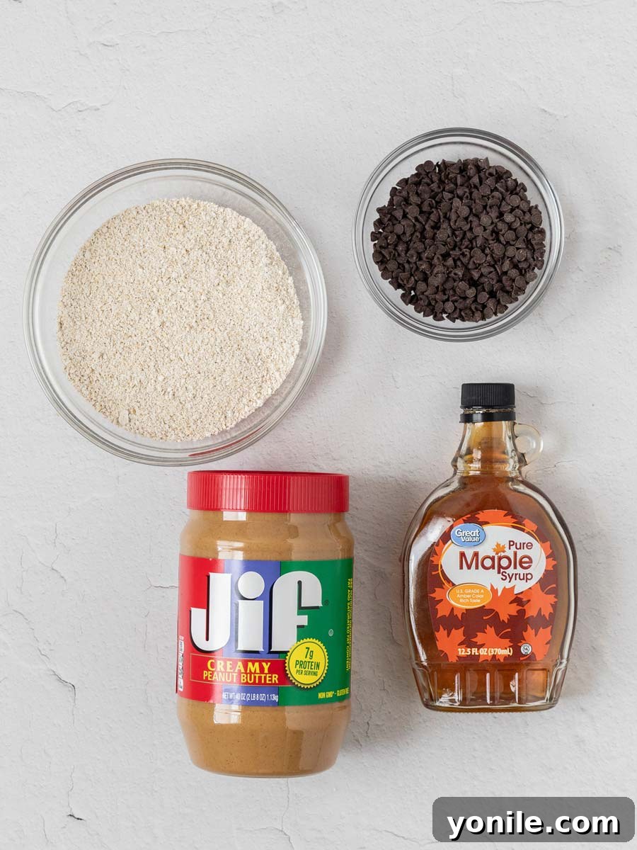 Decadent Chocolate Peanut Butter Oat Bars 3 A curated selection of ingredients laid out for no-bake chocolate peanut butter oatmeal bars, including oats, peanut butter, maple syrup, and chocolate chips.