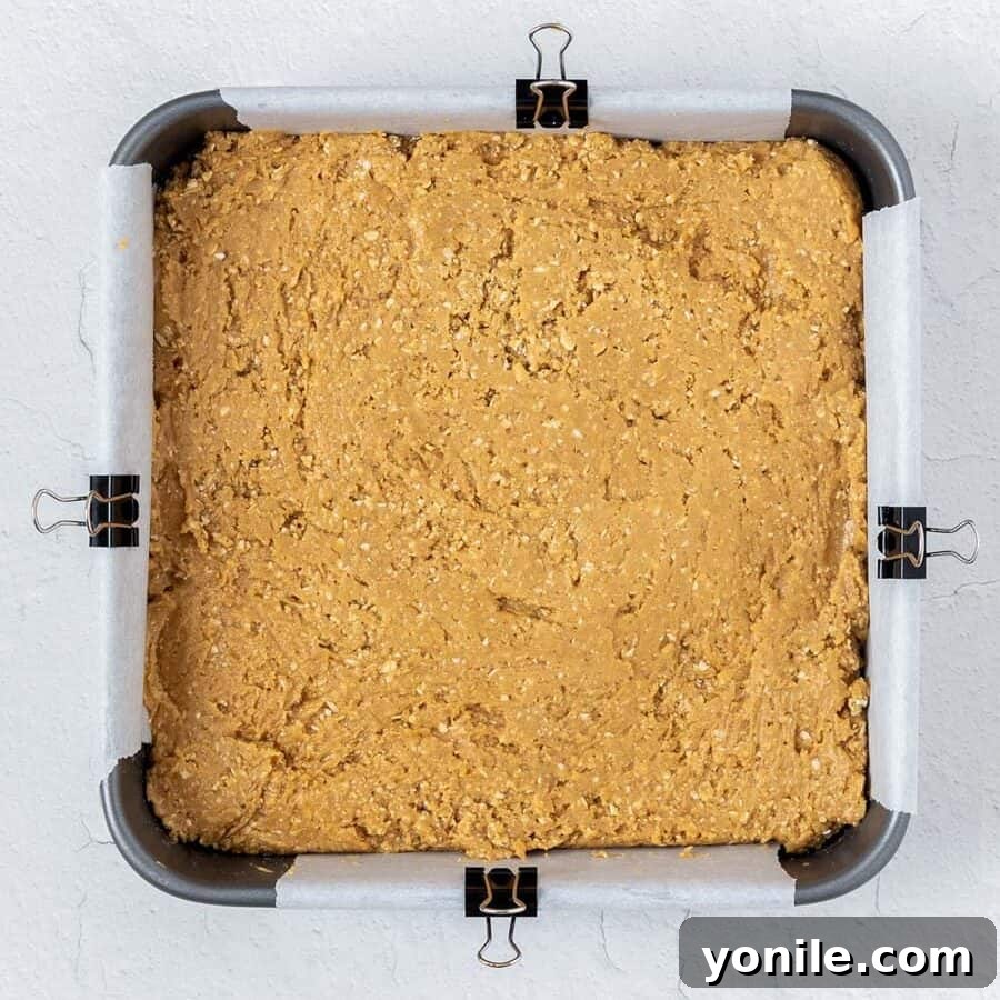 Decadent Chocolate Peanut Butter Oat Bars 5 The peanut butter oatmeal mixture evenly pressed into a square baking pan, ready for the chocolate topping.