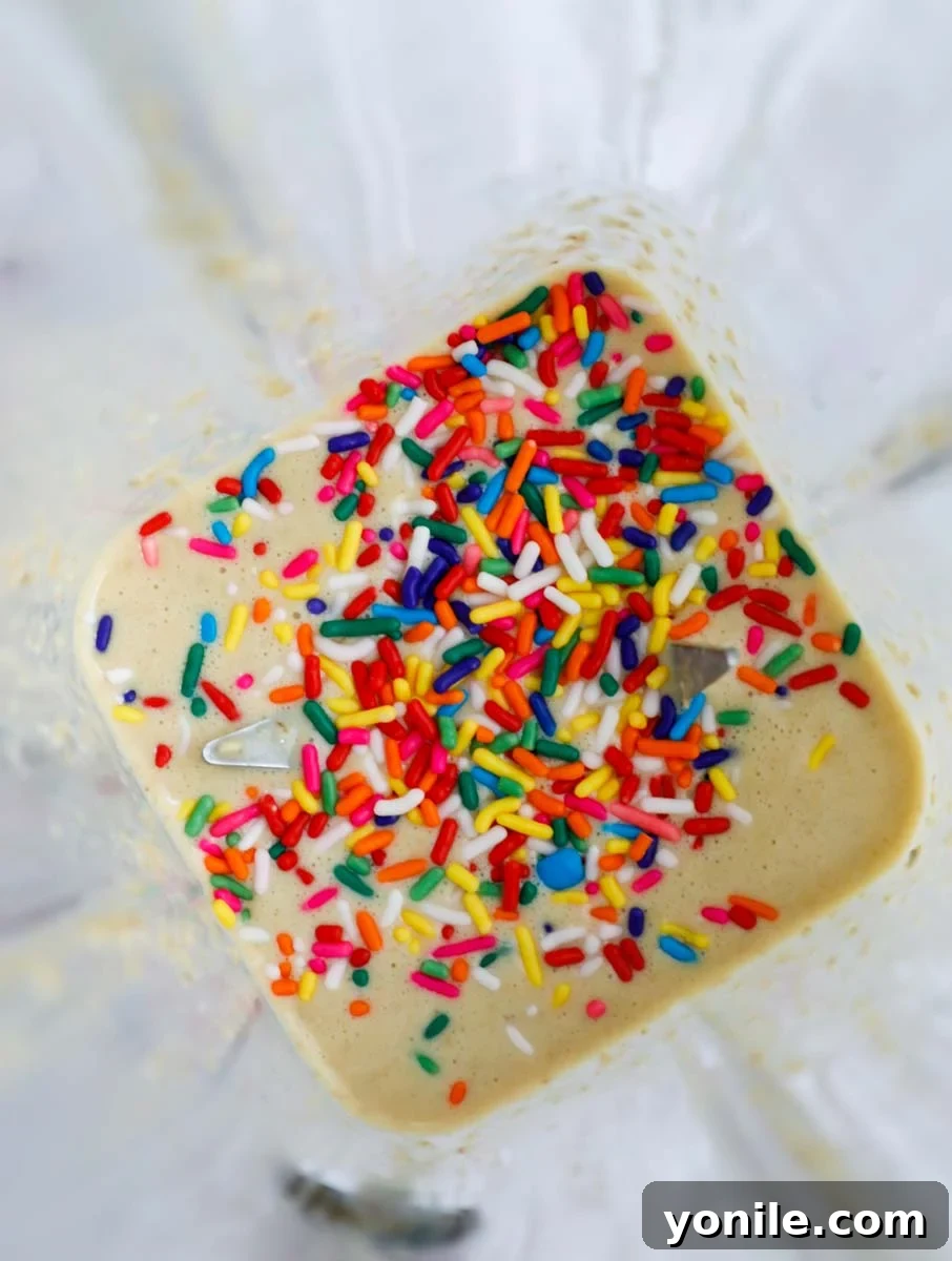 Rainbow Oat Cake Delight 6 Smooth batter being gently mixed with sprinkles in a blender.