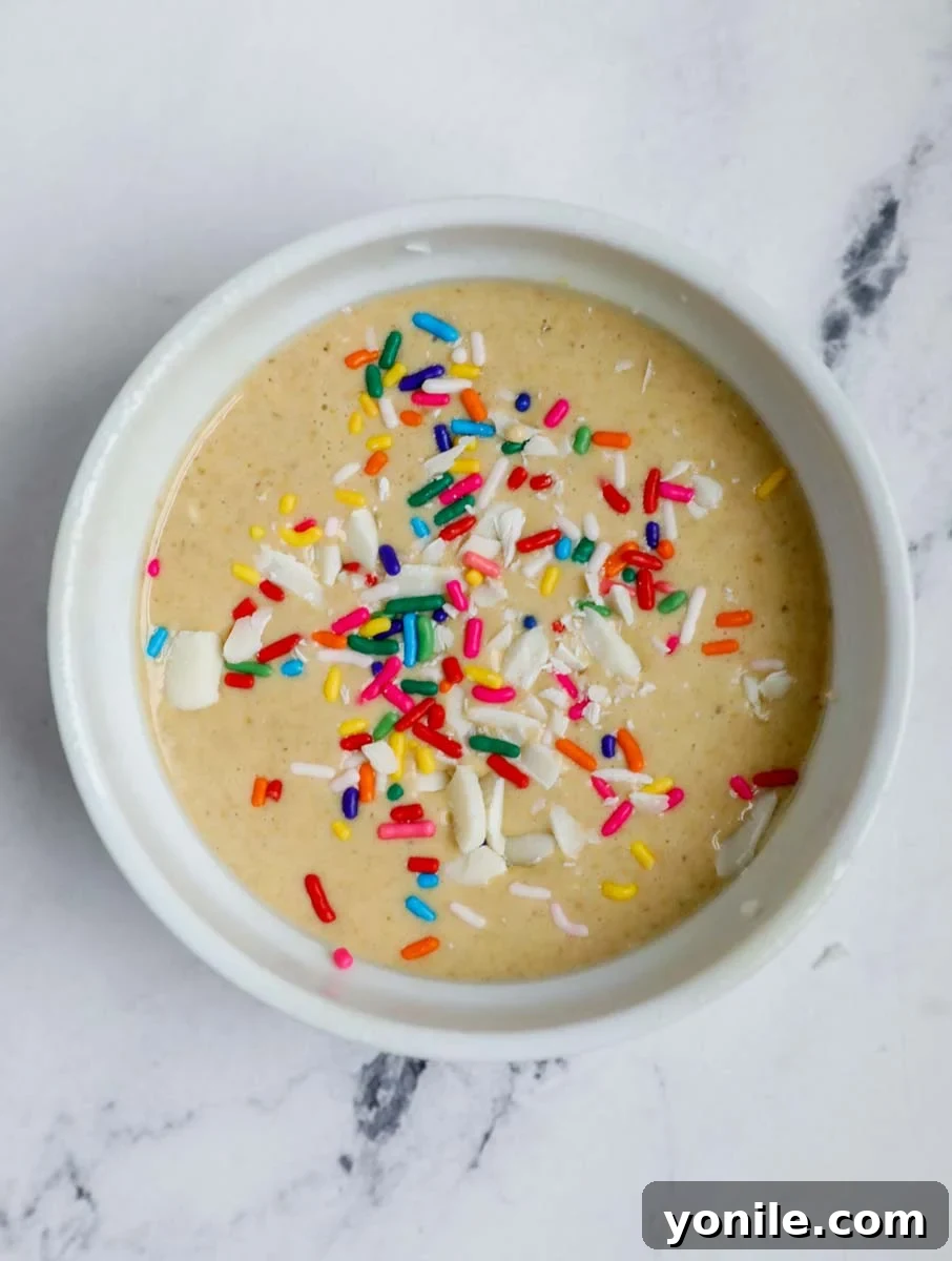 Rainbow Oat Cake Delight 7 Funfetti baked oatmeal batter poured into a greased ramekin, ready for baking.
