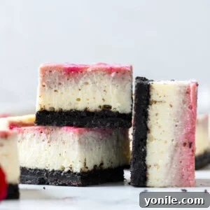 Two cheesecake bars stacked up with one on the side, showcasing the rich layers and vibrant raspberry swirl.