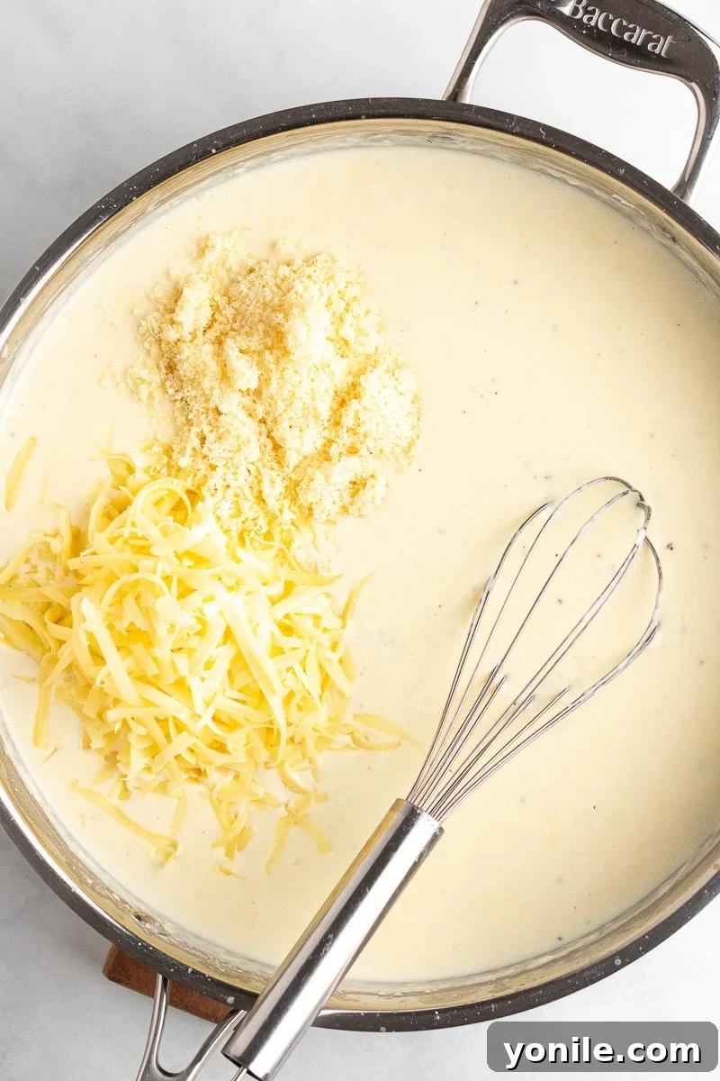 Velvety Spinach Macaroni and Cheese 4 Creamy white sauce with generous amounts of freshly shredded sharp white cheddar and Parmesan cheeses being added and melting.