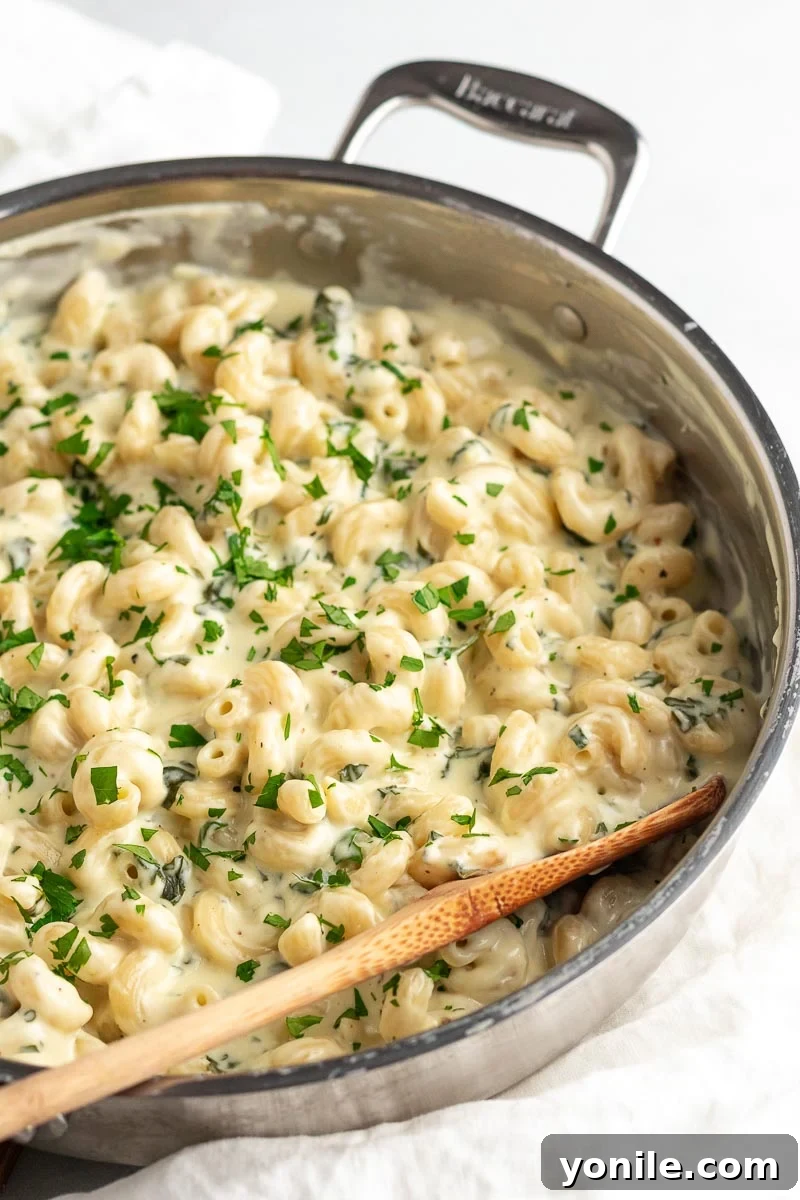 Velvety Spinach Macaroni and Cheese 10 Side view shot of creamy spinach mac and cheese in a skillet, showcasing its appealing texture and rich consistency.