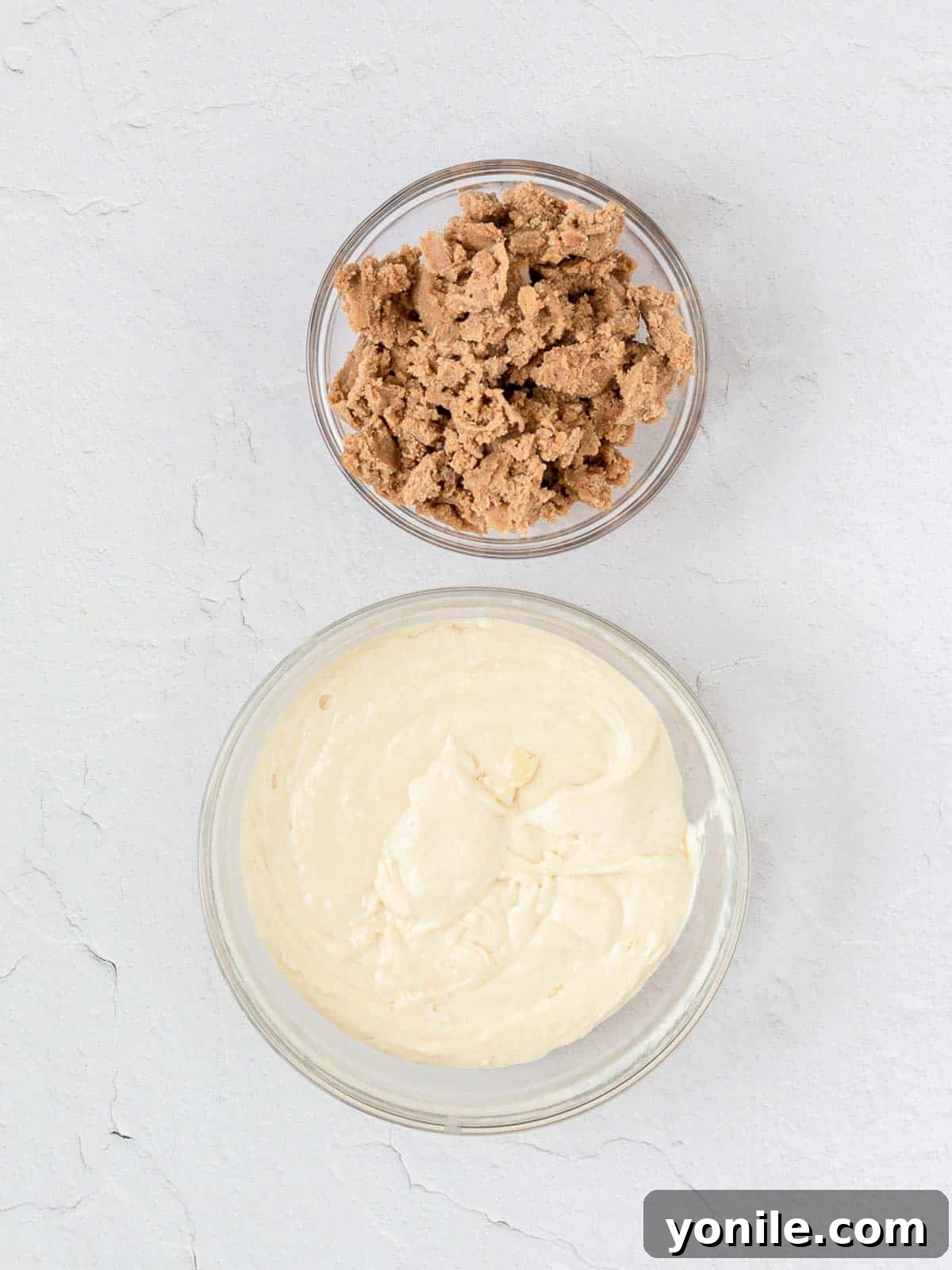 Cake batter spread in a baking pan, with the uncooked streusel mixture waiting to be sprinkled on top.