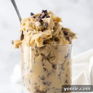 edible cookie dough in a clear glass with a spoon inside