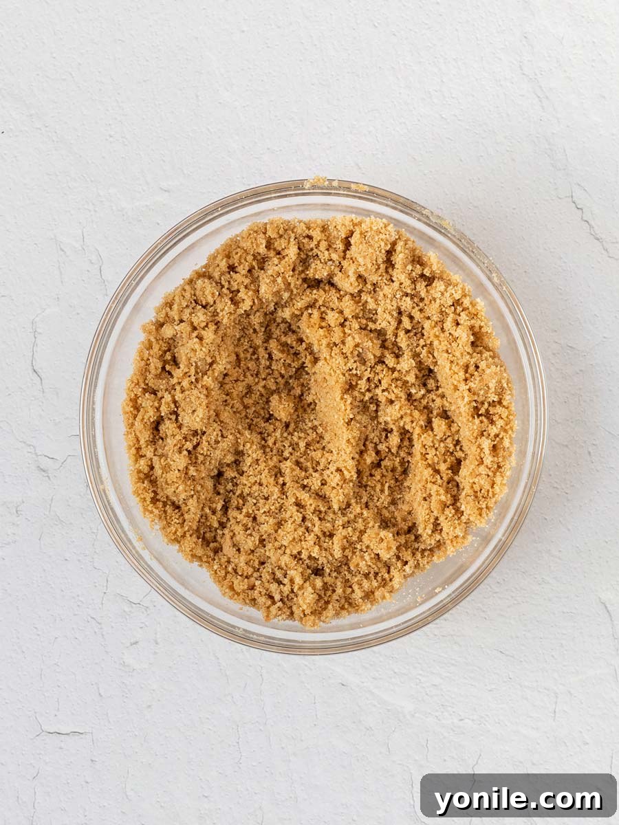 Finely crushed graham cracker crumbs in a mixing bowl, ready to be combined for the crust.